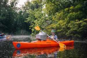 Волонтерка на помаранчевому каяку в плавнях Дніпра везе з води корпус старого телевізора