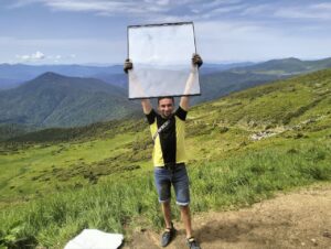 Волонтер тримає новий склопакет для притулку під Говерлою на тлі Карпат