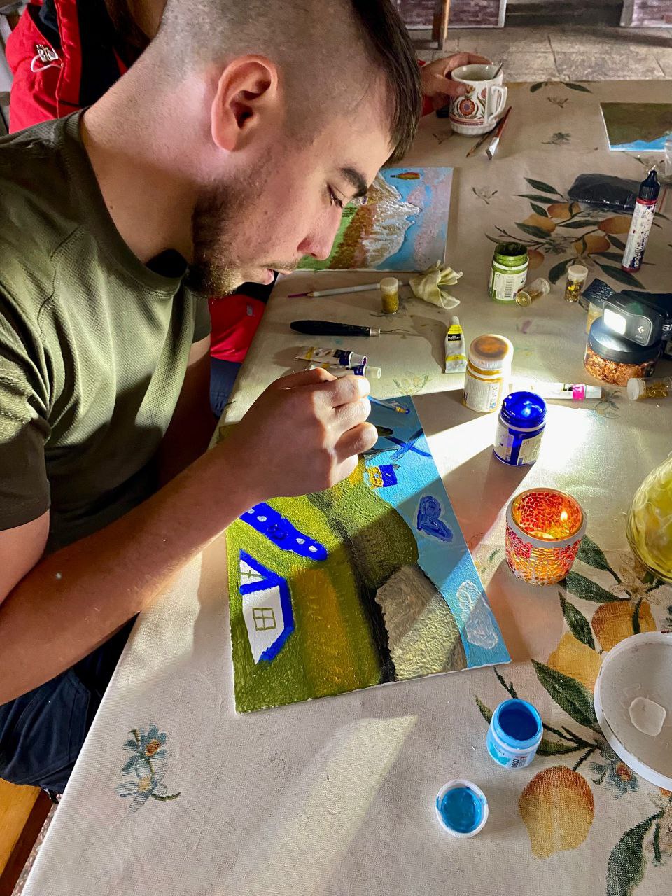 Малювання картини під час арт-терапії в гірському притулку: учасник зосереджено працює над деталями пейзажу