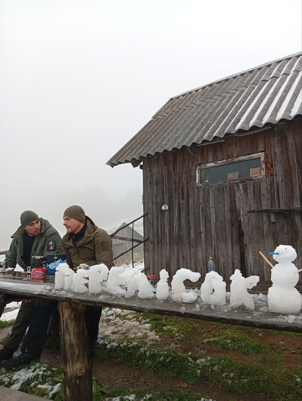 На столі перед гірським будиночком викладені з льоду літери 'Перелісок', поруч — маленький сніговичок