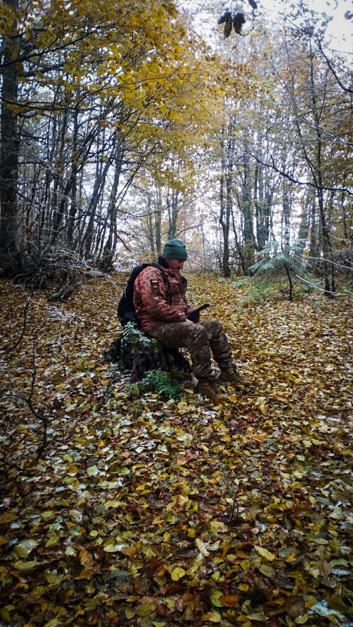 Учасник сидить на пеньку в лісі, відпочиває під час маршруту.