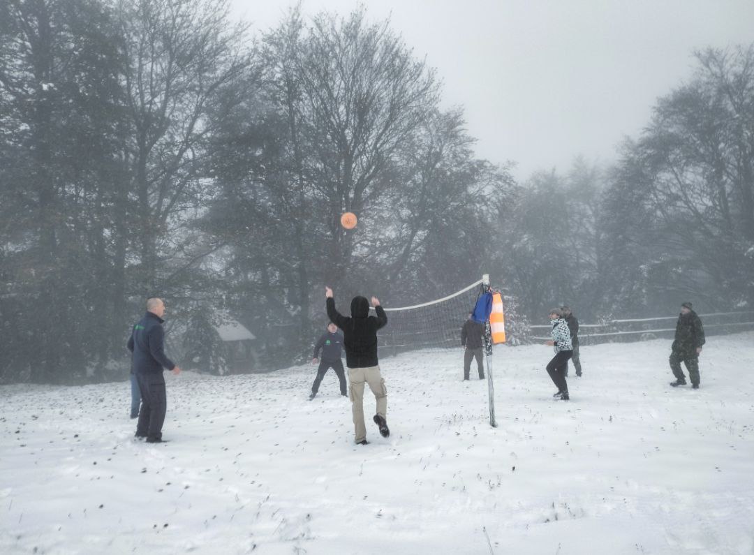 Учасники програми грають у волейбол просто неба на засніженій галявині в тумані.