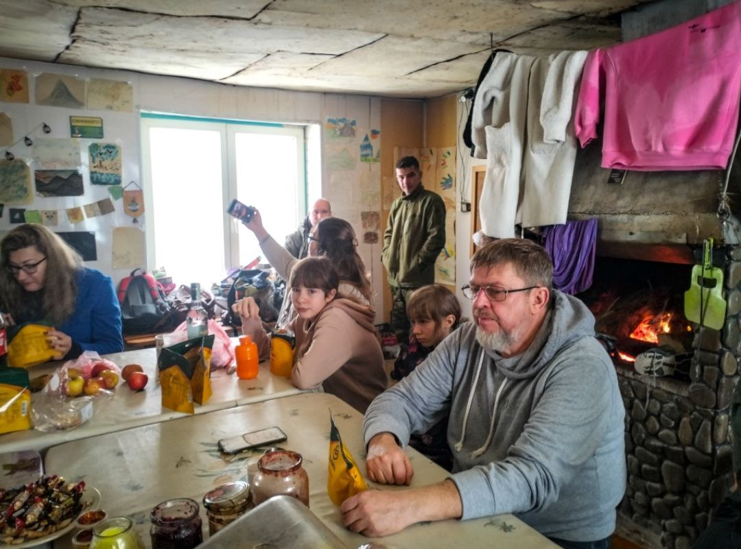 Учасники програми відпочивають у туристичному притулку біля каміна. На стіні — дитячі малюнки.