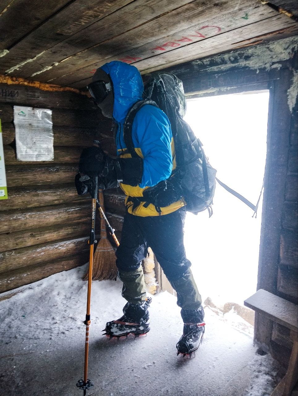 Рятувальник у зимовому спорядженні всередині гірського укриття з трекінговими палицями та кішками